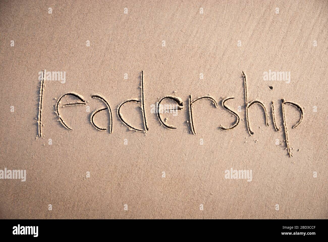 Handwritten message of leadership written in clean smooth sand Stock Photo