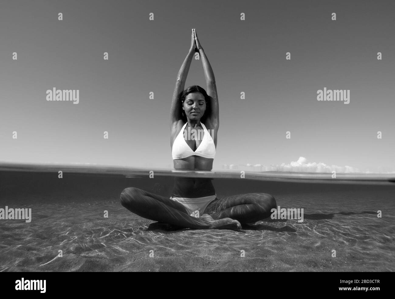 Attractive woman practices yoga in the water at Lahaina, Maui, Hawaii. Stock Photo