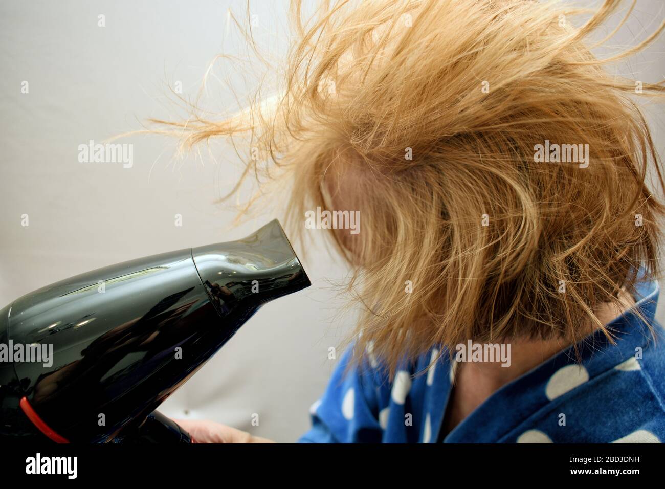 The woman washed her hair. Then she dries her hair with a hairdryer ...