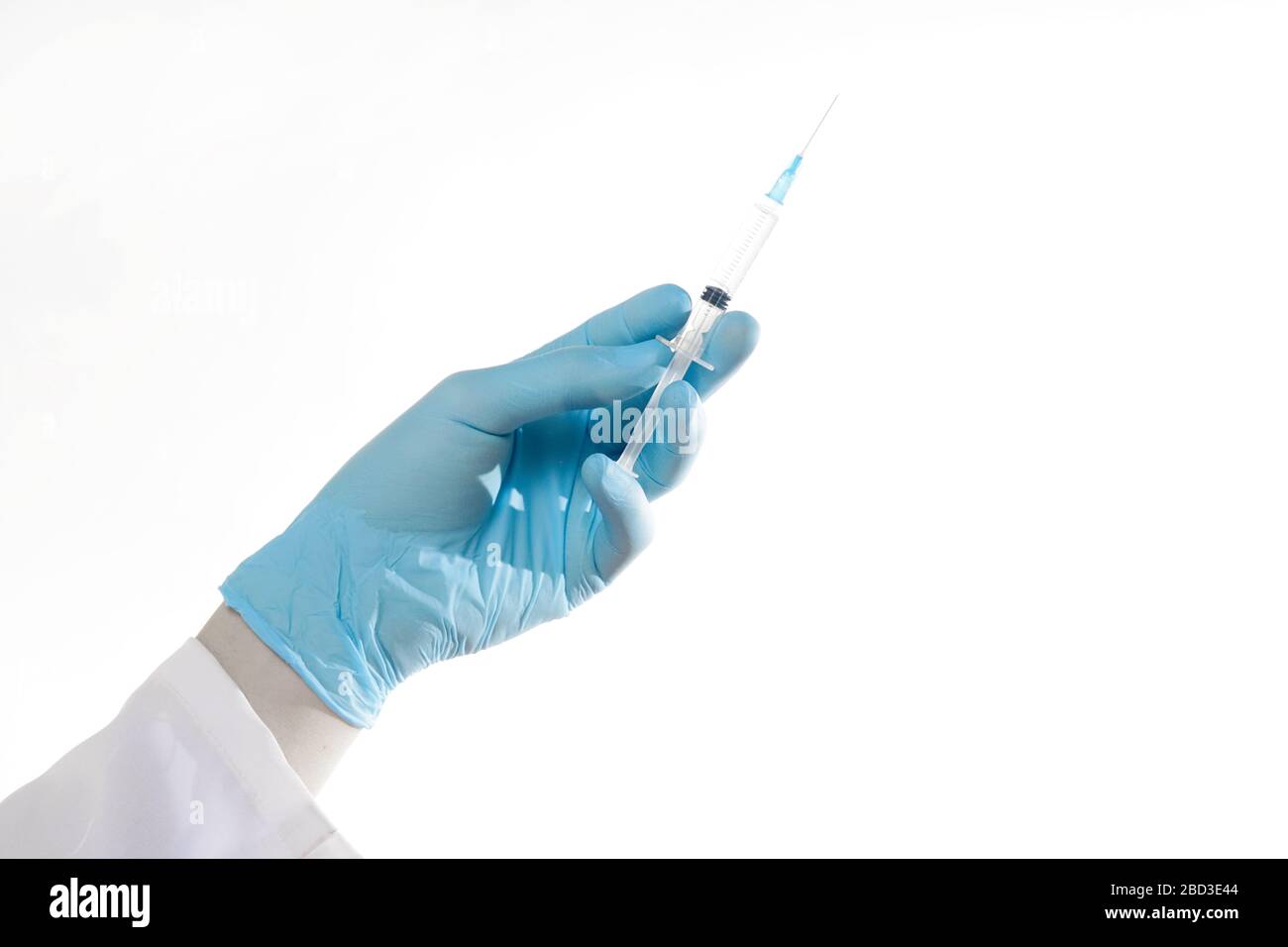 Closeup hand in rubber blue glove holding transparent syringe without cap. Isolated on white background. Vaccination concept Stock Photo