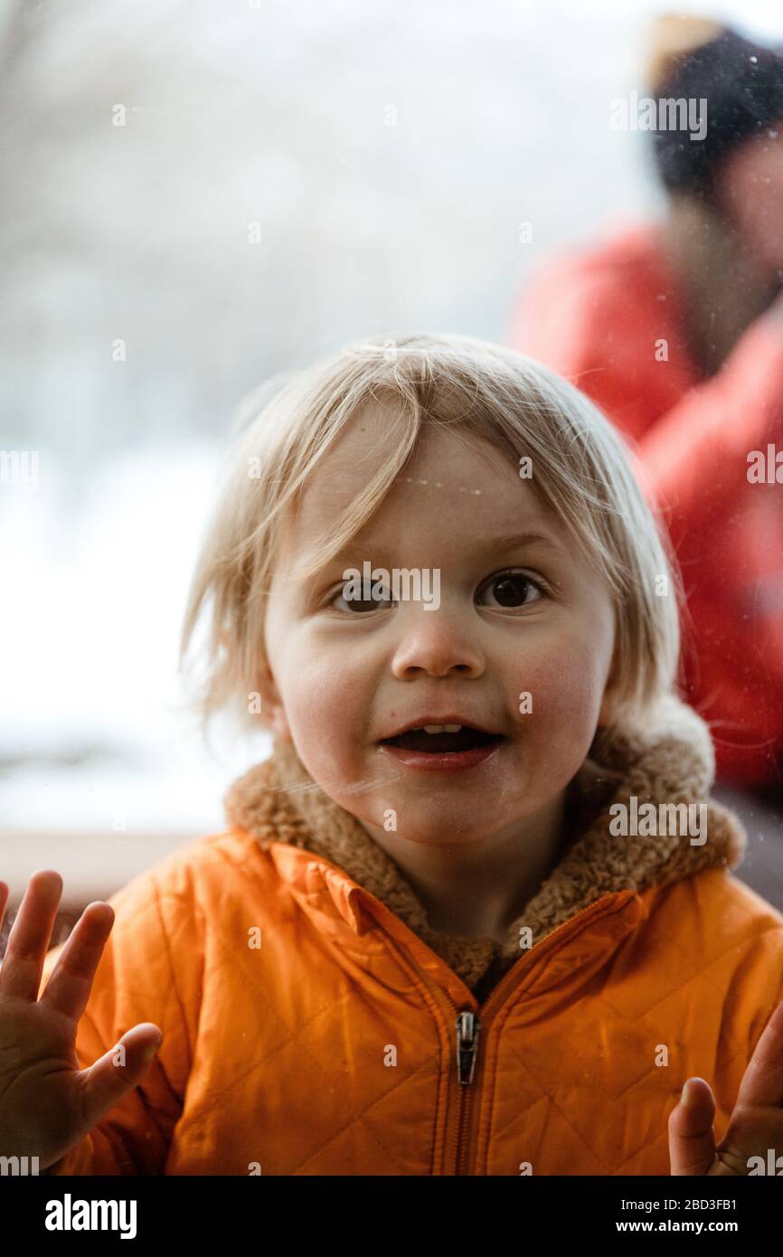 3 year old girl smiles through window at her uncle during quarantine Stock Photo