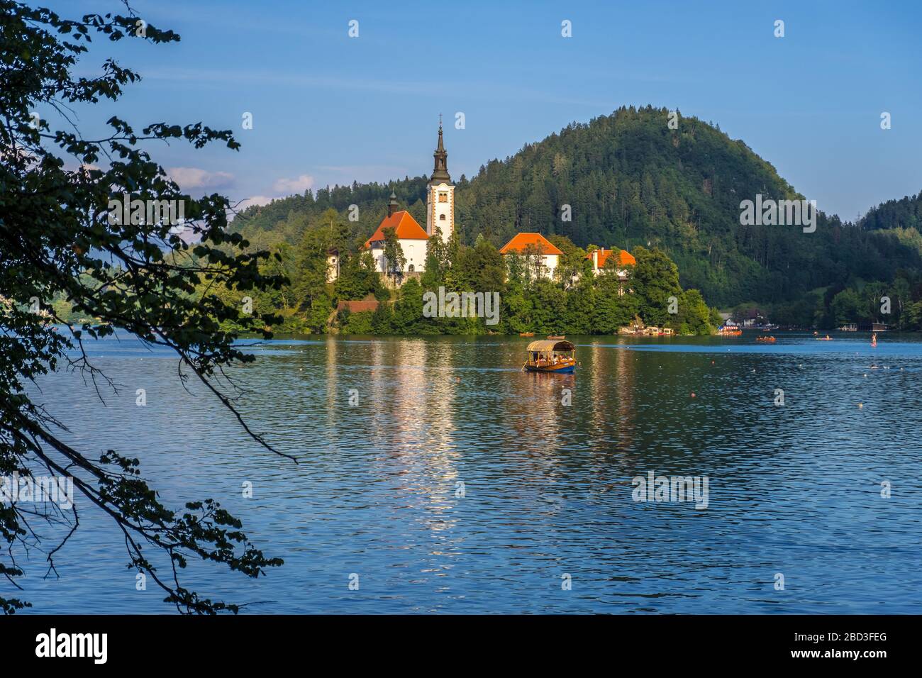 Bled, Slovenia - August 09, 2019: Amazing Bled Lake at sunset with church dedicated to the Assumption of Mary on a small island and Pletna wooden boat Stock Photo