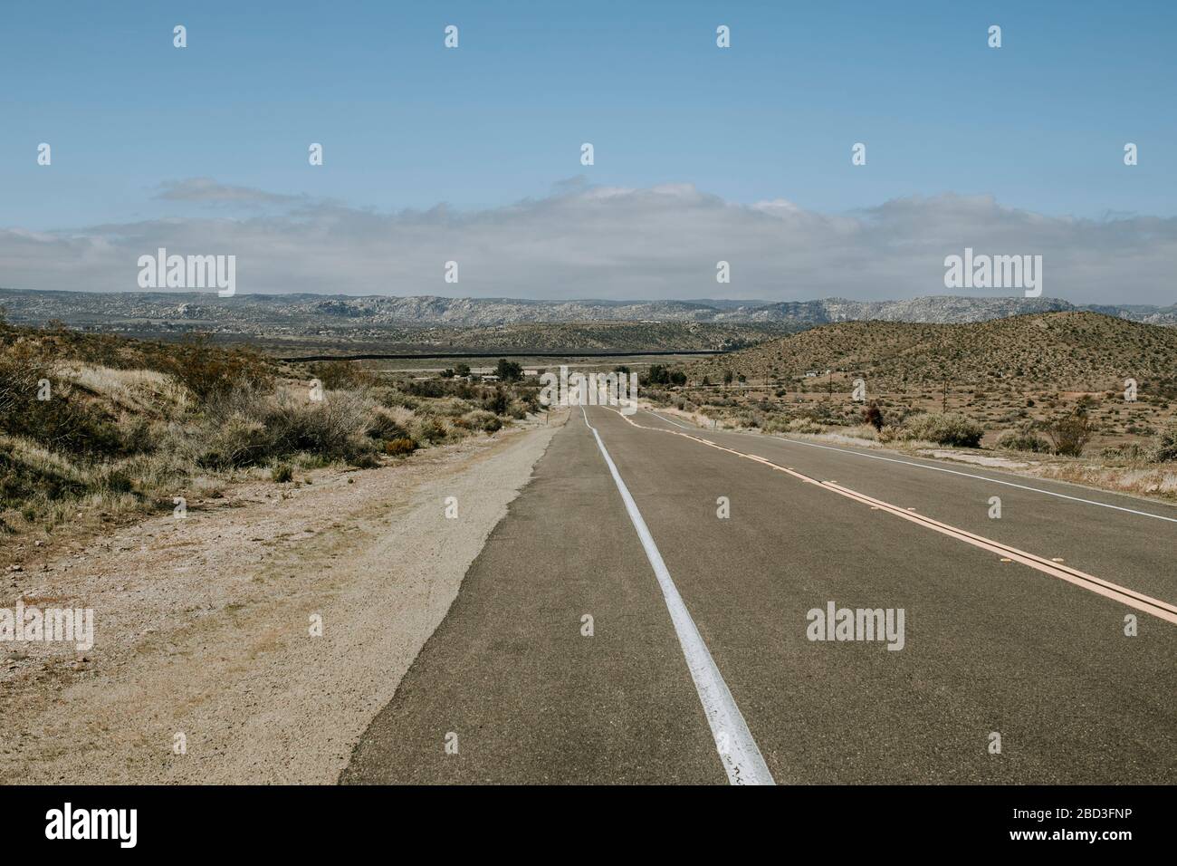 Lonely road with US Mexico border wall in distance near Jacumba, CA Stock Photo