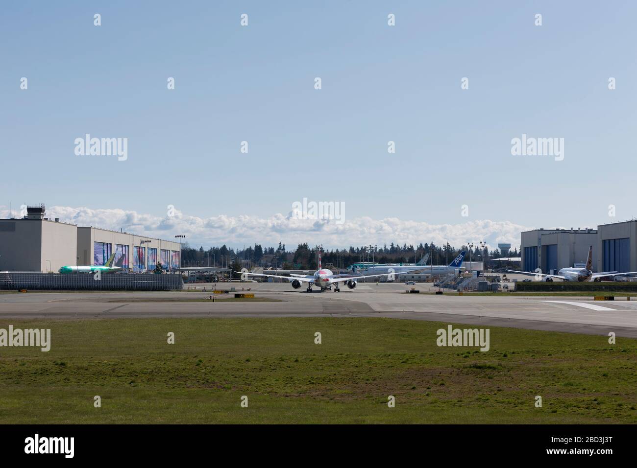 A 787-8 Dreamliner for American Airlines is towed on the Boeing Flightline at the Boeing Factory in Everett, Washington on Monday, April 6, 2020. Boeing has extended the temporary suspension of production operations at all Puget Sound area and Moses Lake sites until further notice.  In the distance are the Boeing Everett Factory paint hangars where a majority of Boeing’s wide-body airplanes are painted before the final flight test. Stock Photo