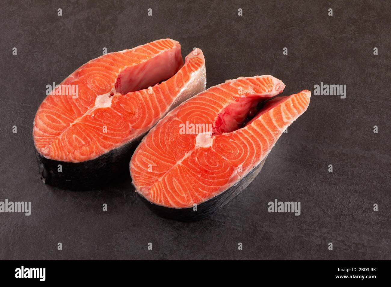 Two raw salmon steaks on a black background Stock Photo - Alamy