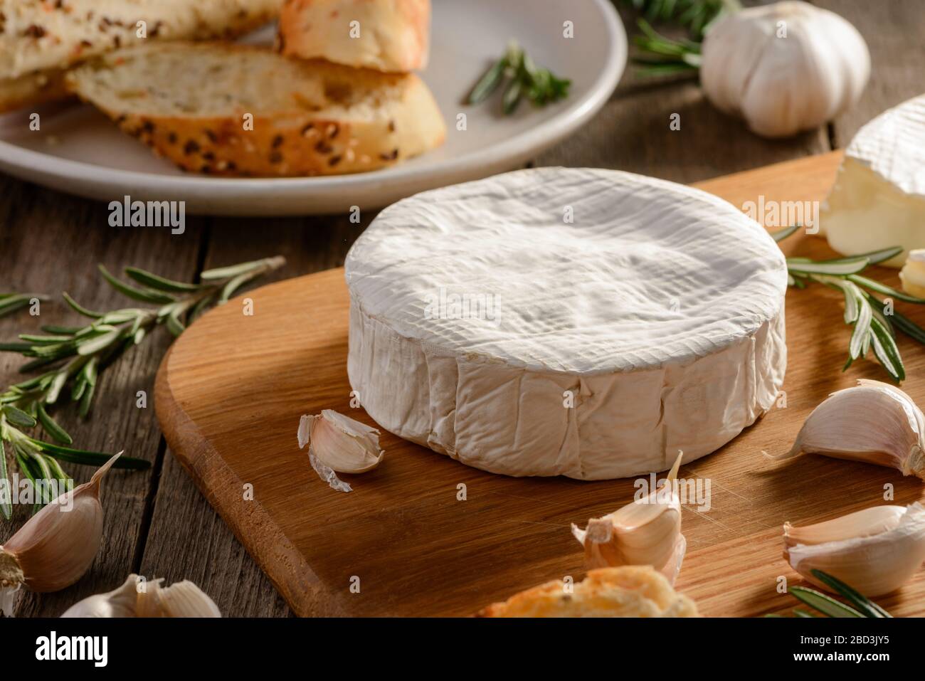 Wheel of Camembert cheese, garlic and rosemary Stock Photo Alamy