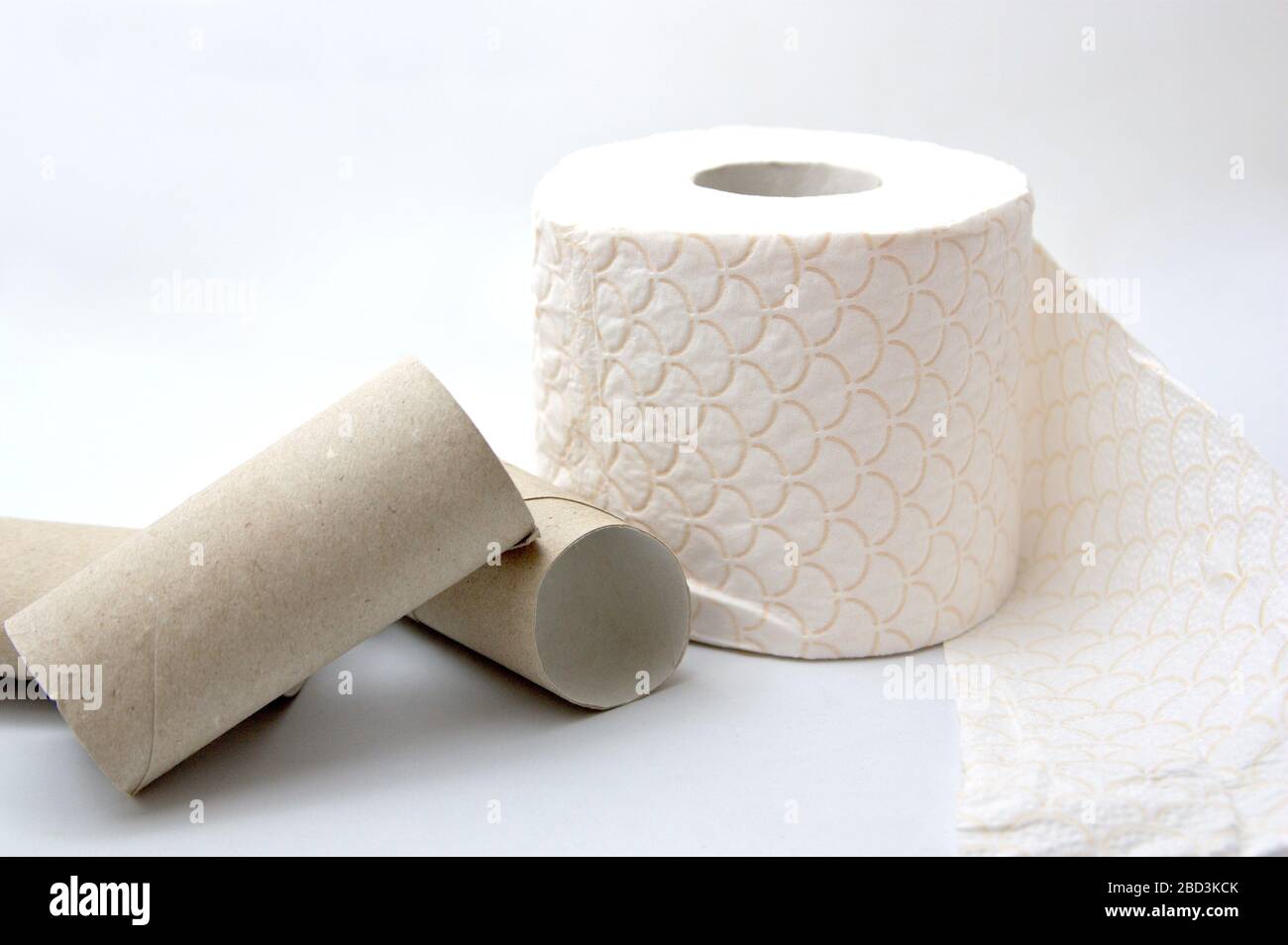 A roll of toilet paper next to cartons of other rolls of paper that have been previously sold out, all with a white background Stock Photo