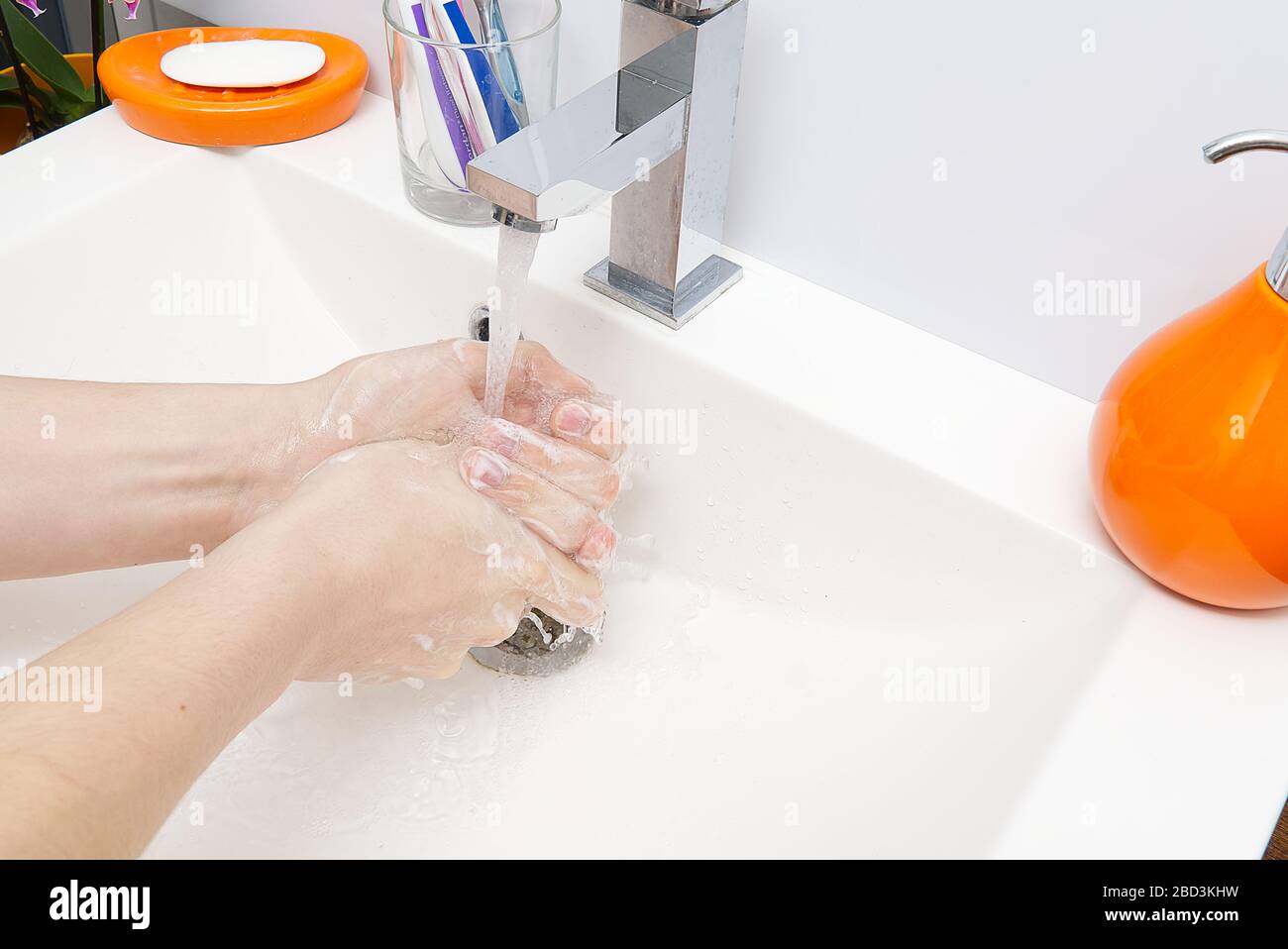 Washing of hands with soap under running water in white sink. close ...