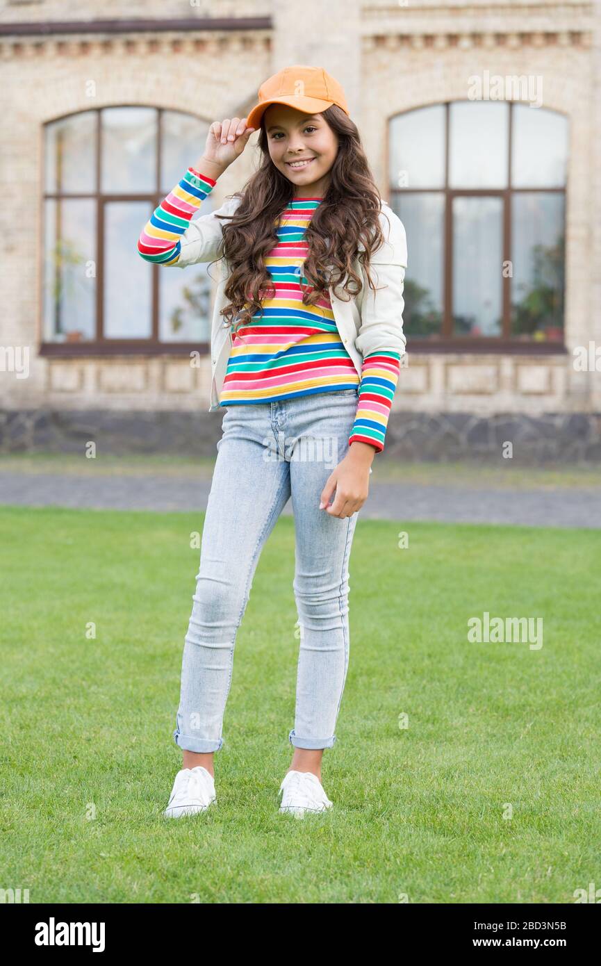 In her own style. childhood happiness. happy girl with long curly hair. pretty child smiling outdoor. kid beauty and fashion. cheerful school girl wear cap. teen in casual style. hairdresser concept Stock In her own style. childhood happiness. happy girl with long curly hair. pretty child smiling outdoor. kid beauty and fashion. cheerful school girl wear cap. teen in casual style. hairdresser concept Stock