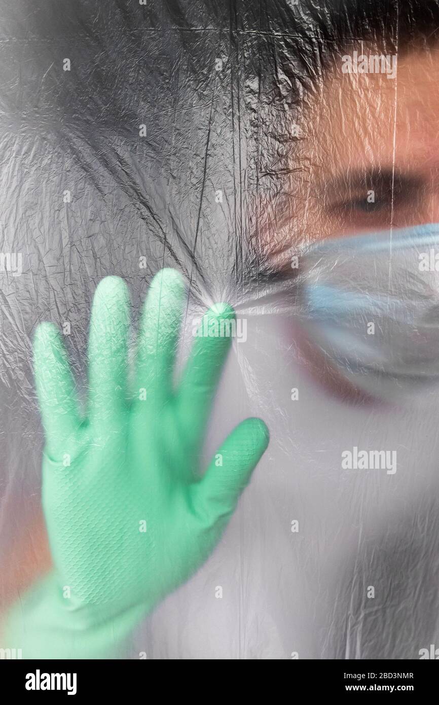 Man in protective mask and gloves self-isolated in his apartment during coronavirus infection, so as not to infect his family, touching isolation memb Stock Photo