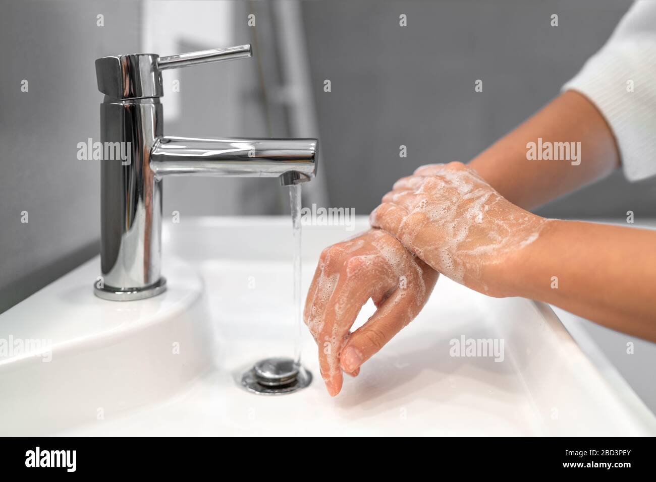Hand washing lather soap rubbing wrists handwash step woman rinsing in water at bathroom faucet sink. Wash hands for COVID-19 spreading prevention. Coronavirus pandemic outbreak. Stock Photo