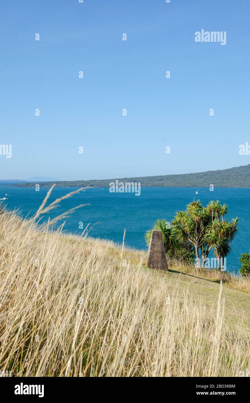 Tall grass and trees overlooking blue ocean and blue sky on sunny day in Devonport Stock Photo