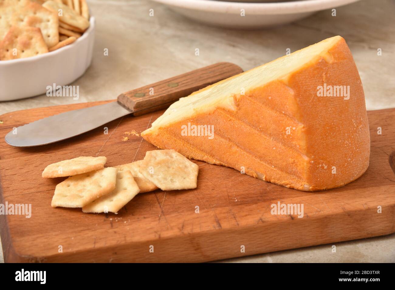 A wedge of gourmet imported Belgium Autumn Cheese with crackers. Stock Photo
