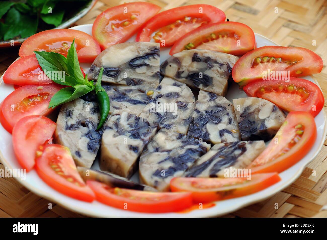 Plate of vegan meal for vegetarian, vegan pie from white straw mushroom, wood ear, black mushroom with jelly, Vietnamese food cut in slice with tomato Stock Photo