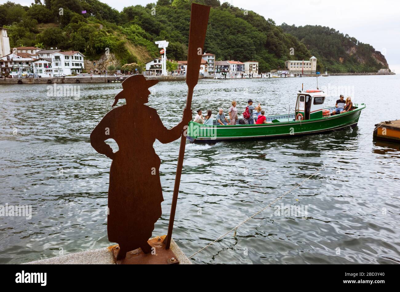 Pasajes, Gipuzkoa, Basque Country, Spain - July 21st, 2019 : Small ferry boat at the pier on the Oyarzun estuary and batelera (boat woman) statue. Inc Stock Photo