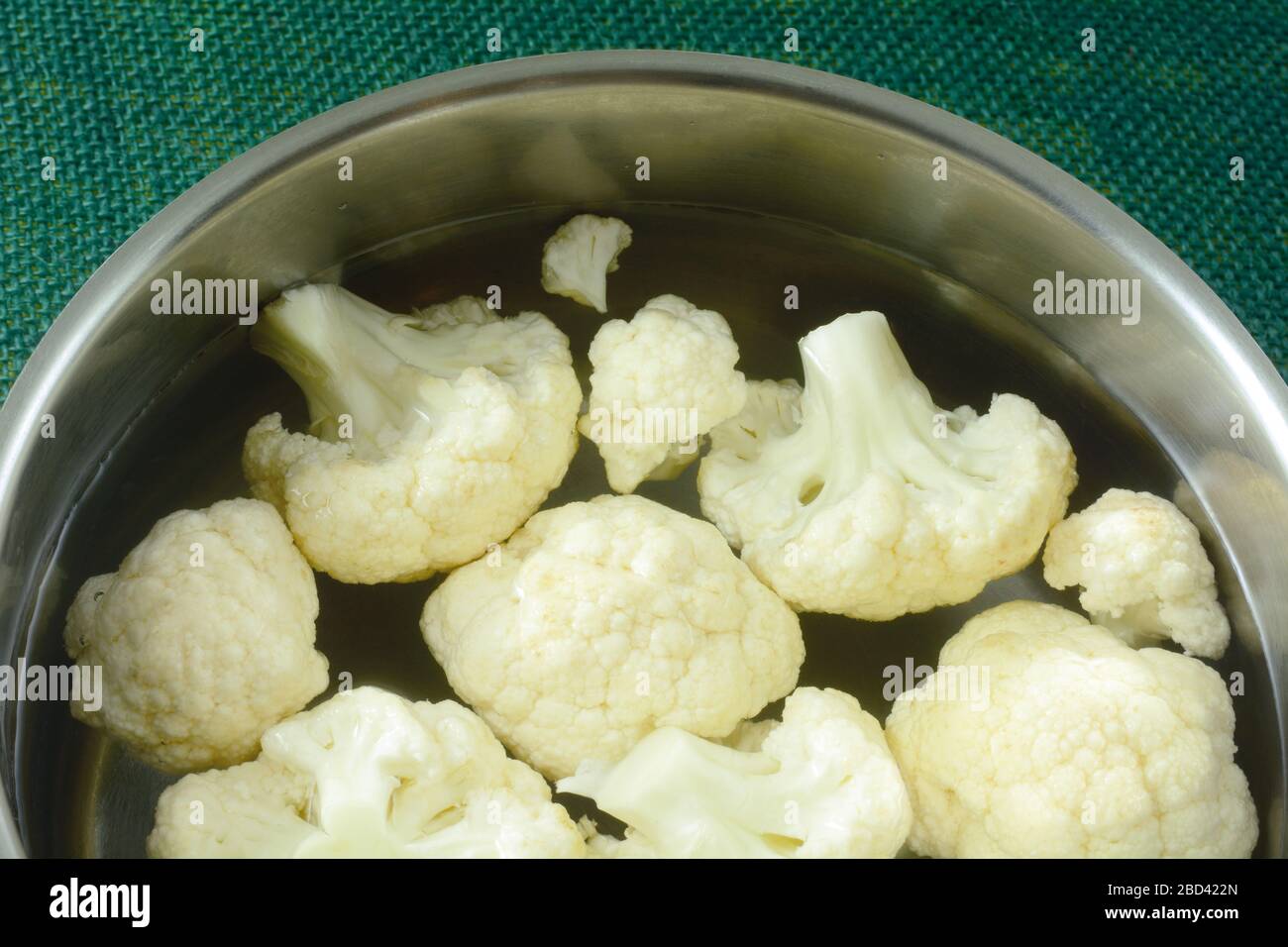 Fresh raw cauliflower florets in water in cooking pan to prepare for boiling Stock Photo