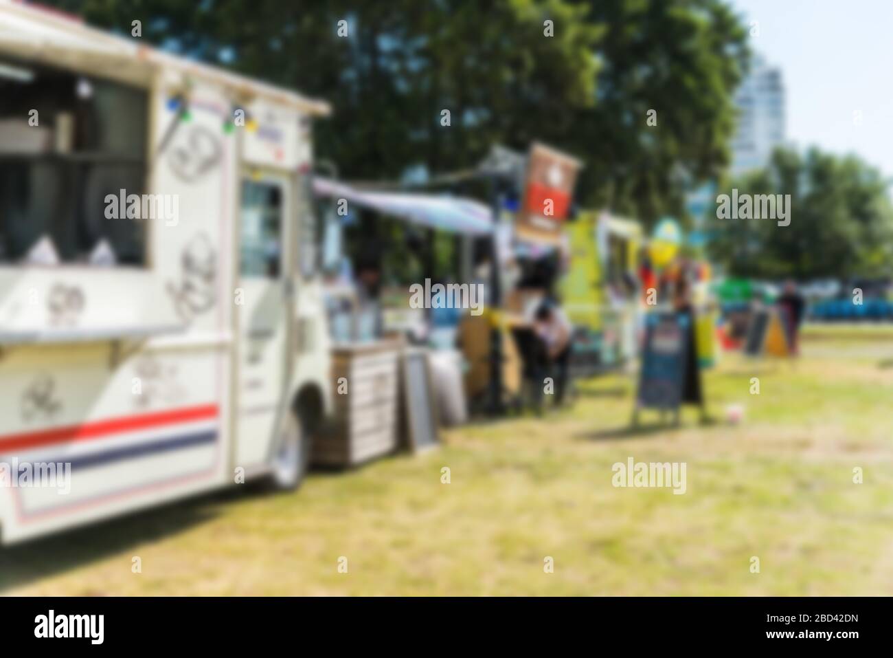 Food trucks and people at a street food market festival, blurred on purpose. Stock Photo