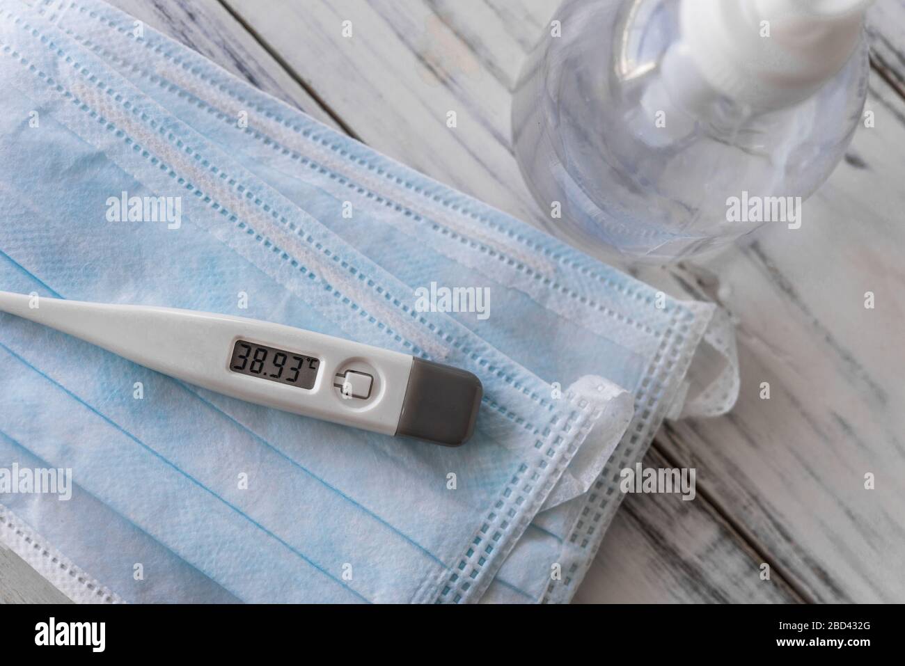 Thermometer with fever, hand sanitizer, and face masks. Coronavirus symptoms. Stock Photo