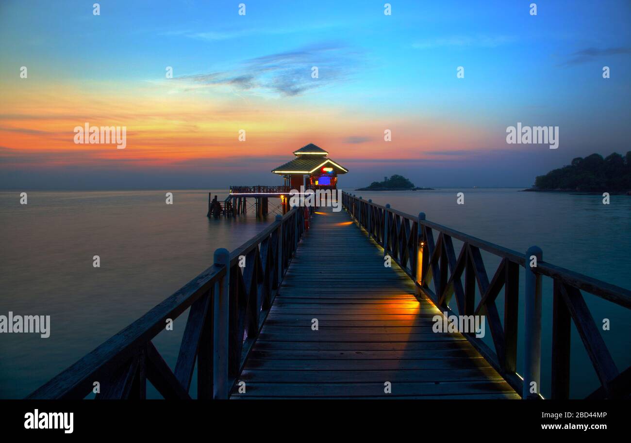 Romantic tropical lagoon sunset on Bintan Island in Indonesia with silhouette of a boat jetty hut. Stock Photo