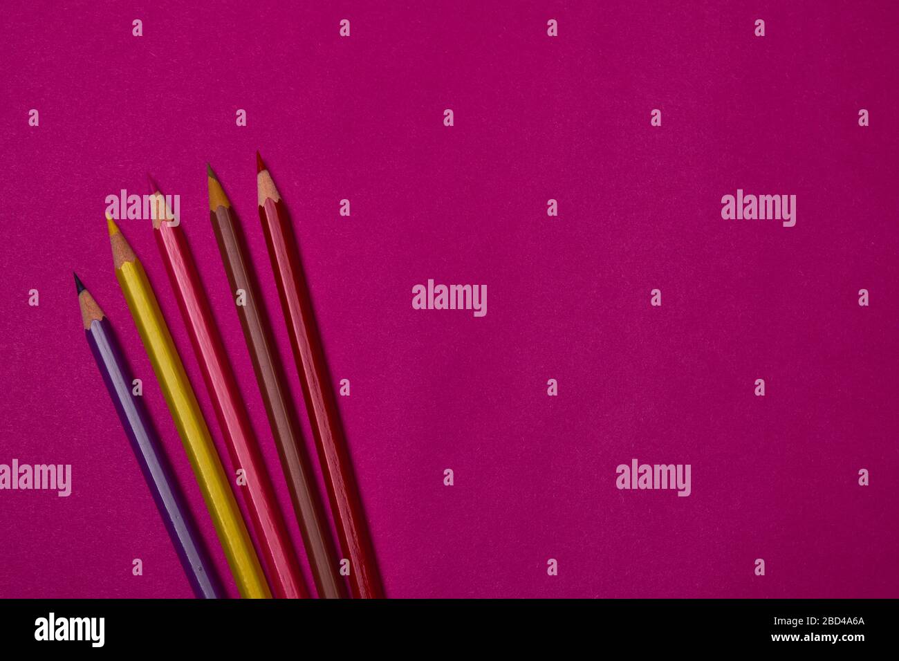 Multi colored crayons at magenta background with copy space. Stock Photo