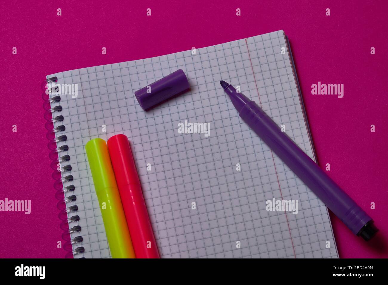 Multi colored felt tip pens and binder notepad at magenta background with copy space. Stock Photo
