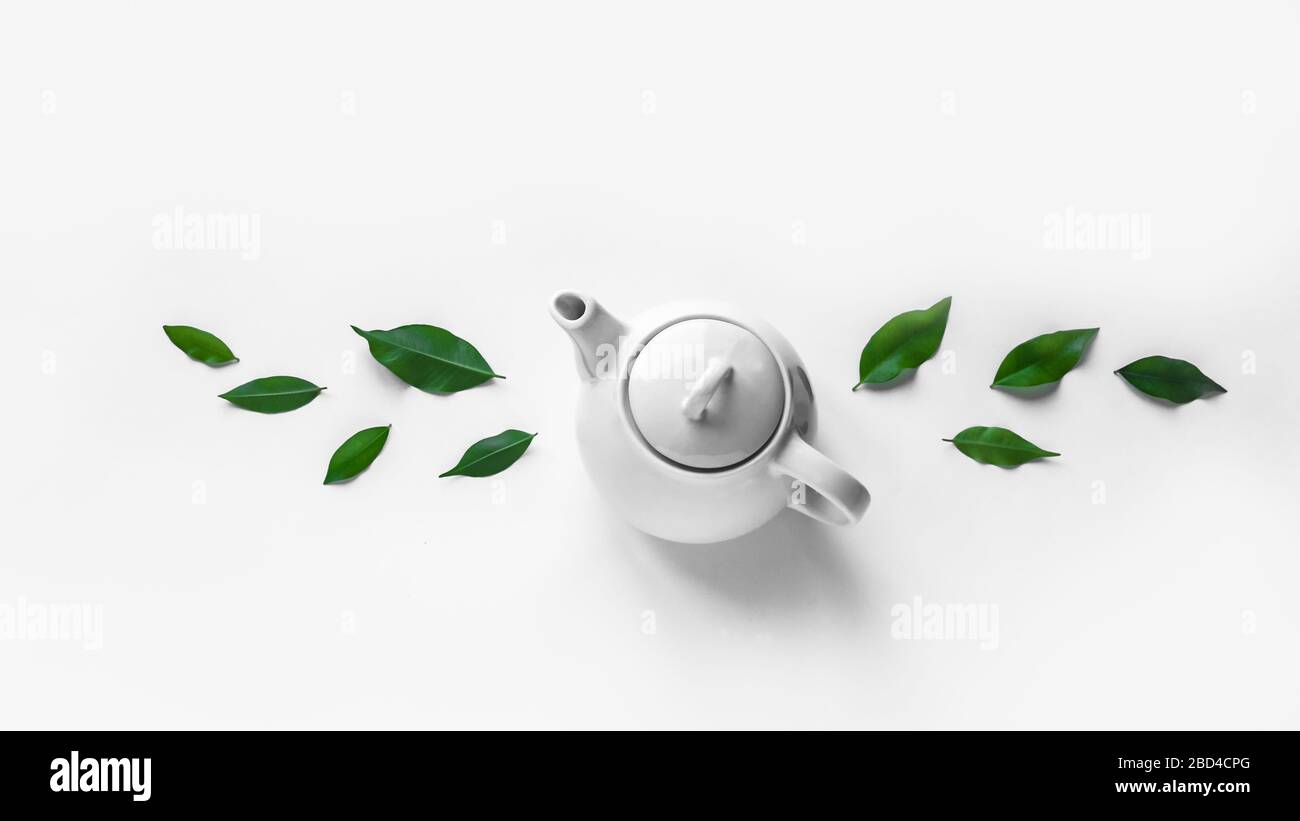 Green Tea white teapot and tea leaves on white background. Organic