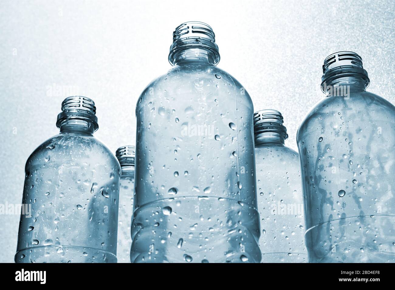 Clear plastic bottles with water drops in monochrome blue white backlit