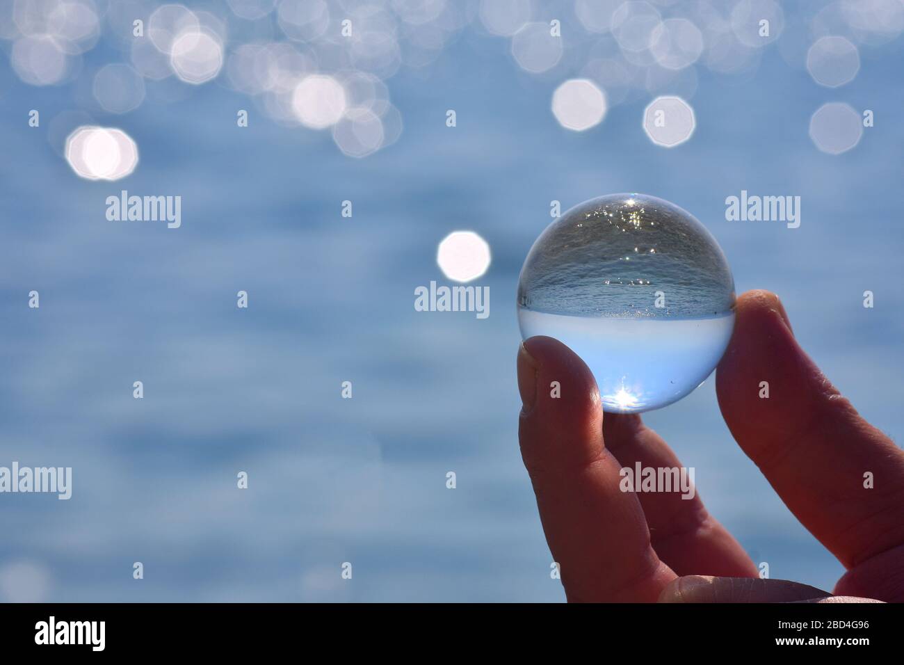 Beautiful summer coast seen through a blue glass ball/ Blue freedom concept/ Ocean Surface Ripples and Clouds in Sky Captured in Glass Ball/ Stock Photo