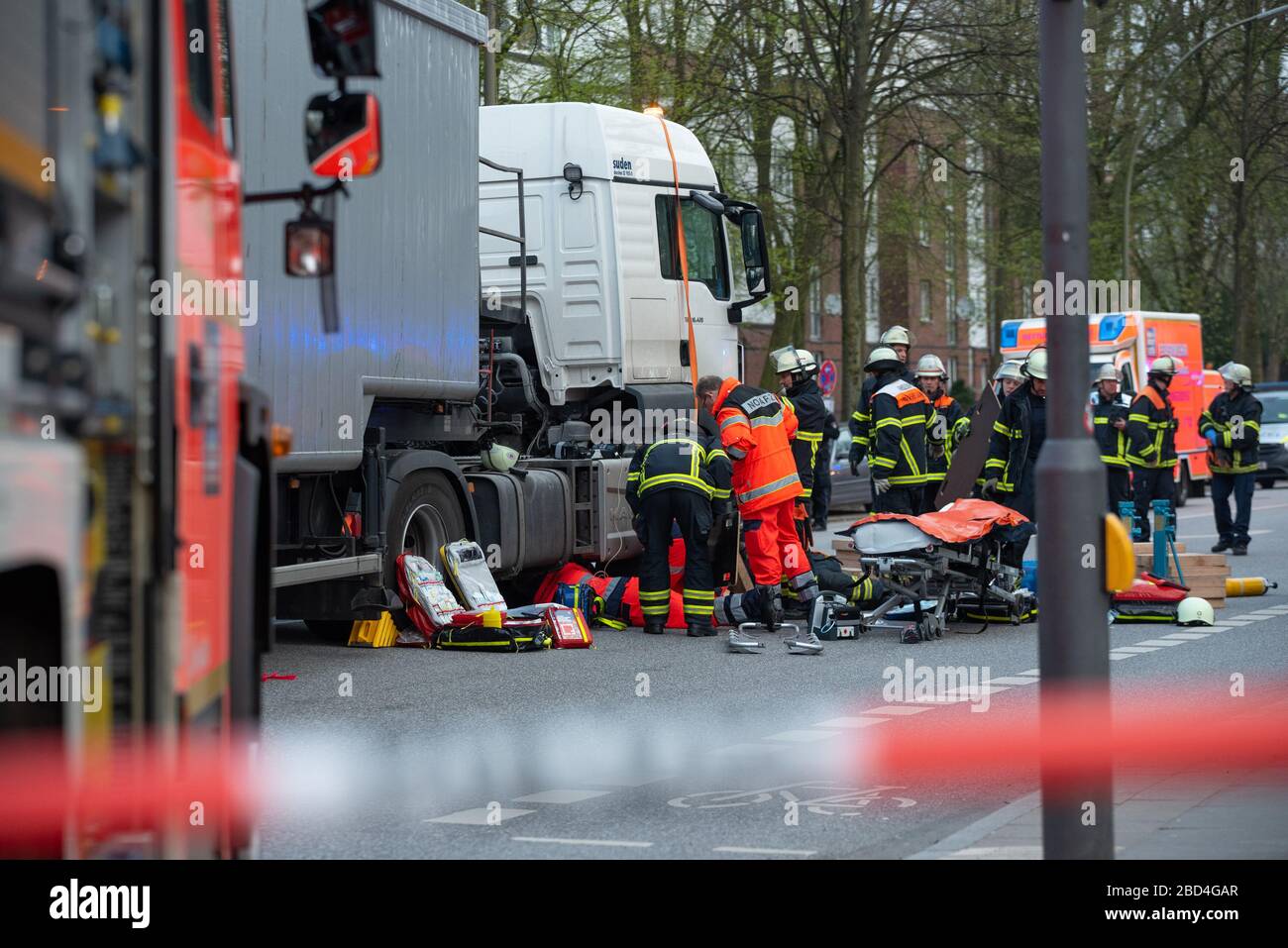 Hamburg, Germany. 07th Apr, 2020. Rescue workers care for the trapped woman and try to free her. According to a fire department press spokesperson, a cyclist was run over by a truck in front of the Lattenkamp subway station on Tuesday morning. She died in the ambulance at the scene of the accident despite resuscitation by the rescue services. Credit: Jonas Walzberg/dpa/Alamy Live News Stock Photo