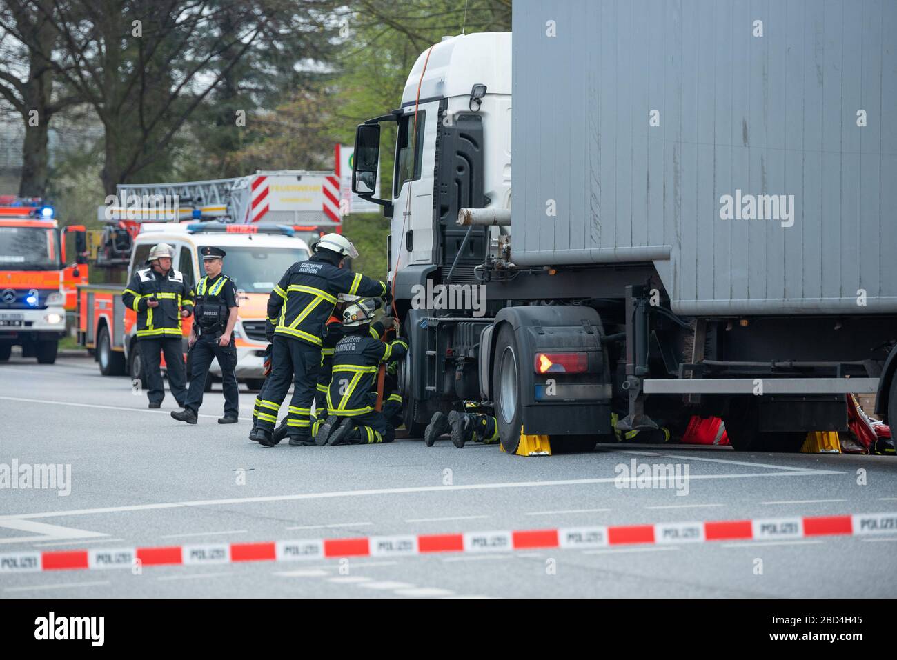 Hamburg, Germany. 07th Apr, 2020. Rescue workers care for the trapped woman and try to free her. According to a fire department press spokesperson, a cyclist was run over by a truck in front of the Lattenkamp subway station on Tuesday morning. She died in the ambulance at the scene of the accident despite resuscitation by the rescue services. Credit: Jonas Walzberg/dpa - ATTENTION: Truck identification was pixelated/dpa/Alamy Live News Stock Photo