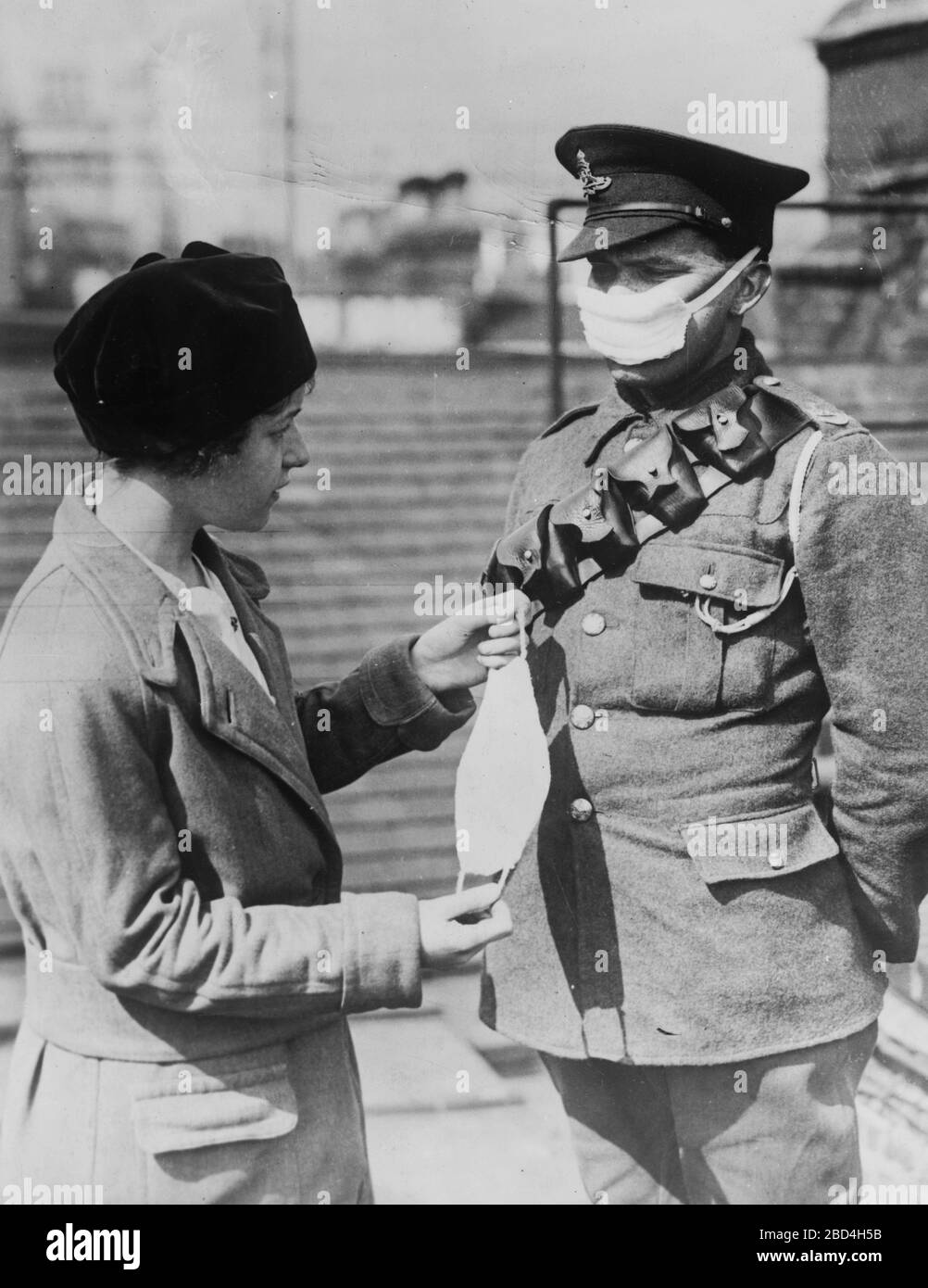 British soldier wearing a face mask to protect against poison gas, standing with a woman holding another face mask, during World War I ca. 1914-1915 Stock Photo