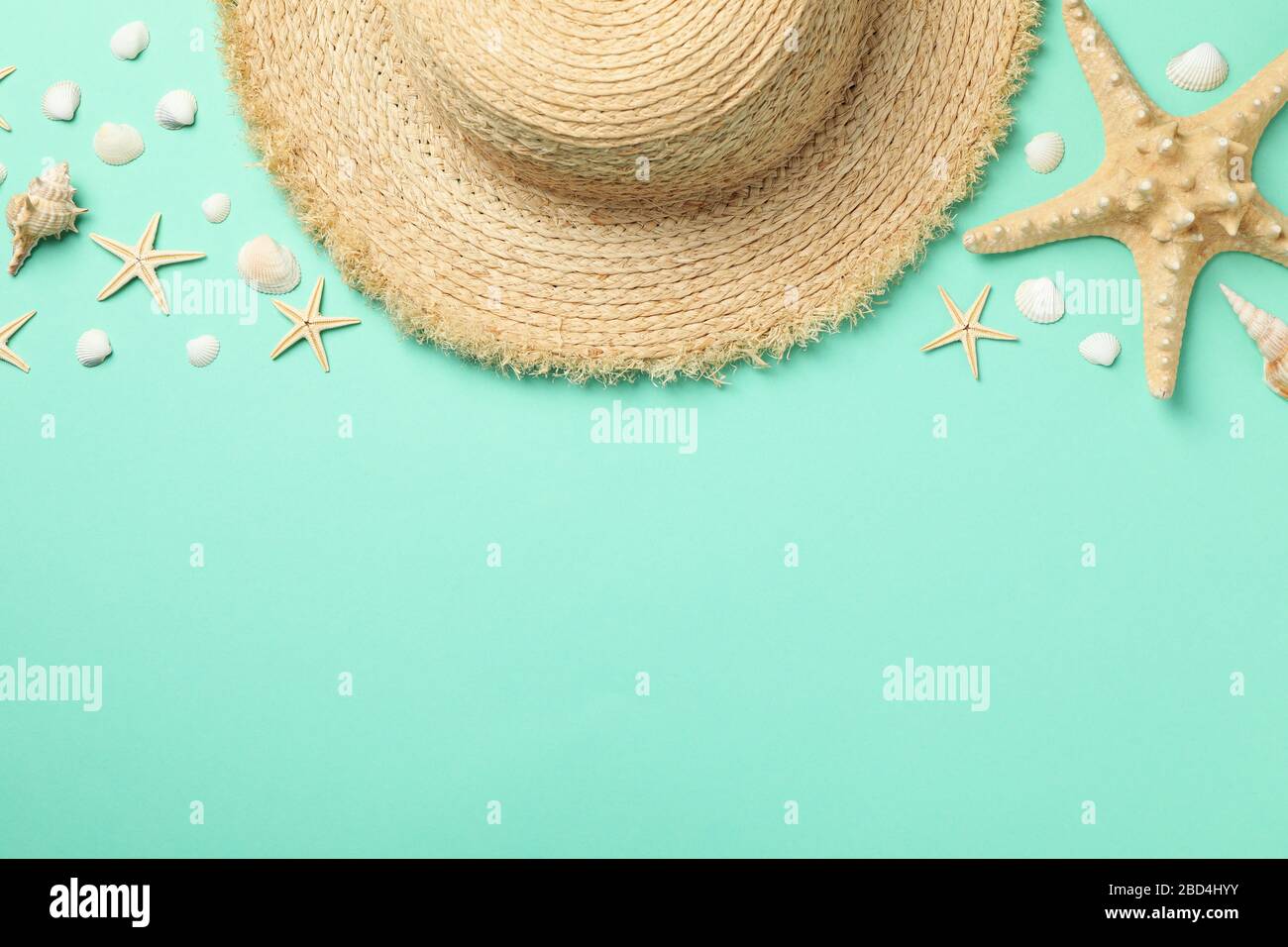 Straw hat and starfishes on mint background, top view Stock Photo