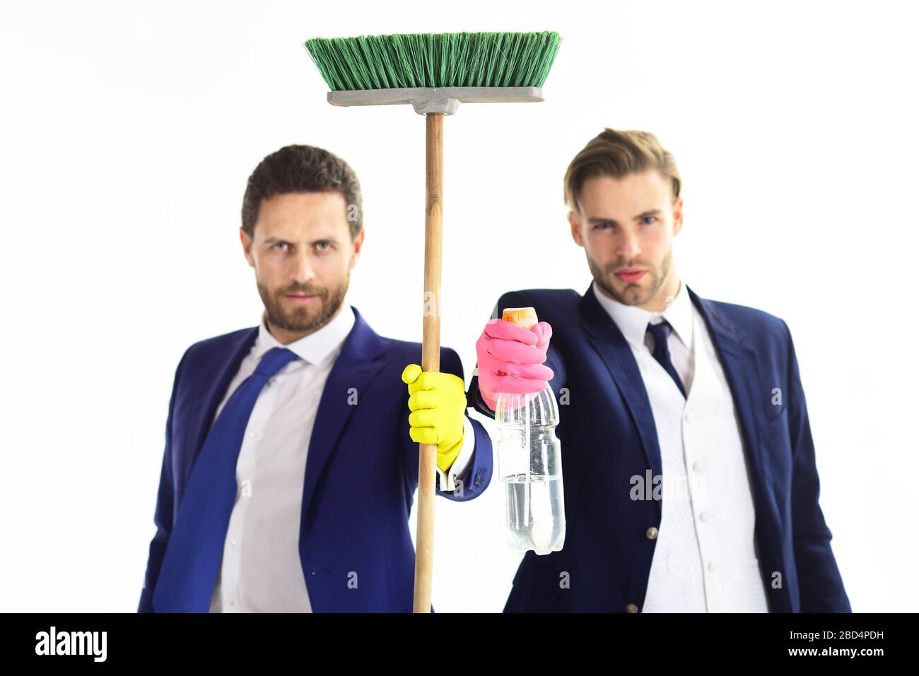 Housework, cleaning service, teamwork, business concept. Business people with beards and mop. Bearded friends in formal suits with serious faces and sweep. Banker and financier hold cleaning supplies. Stock Photo
