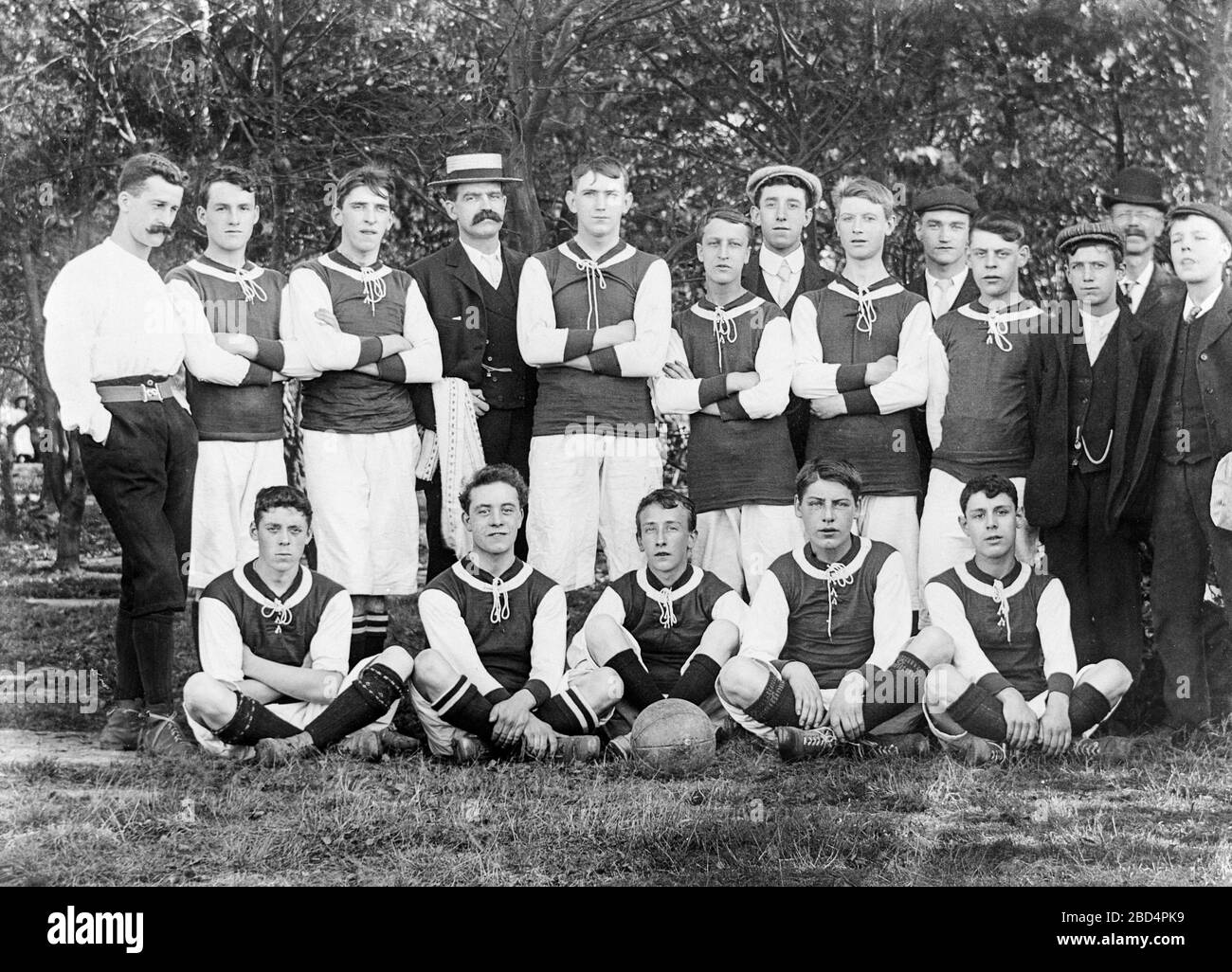 A vintage early Edwardian black and white photograph, taken in England, showing the members of a boys Football, or soccer, team, together with their trainers, coaches, managers etc. Stock Photo