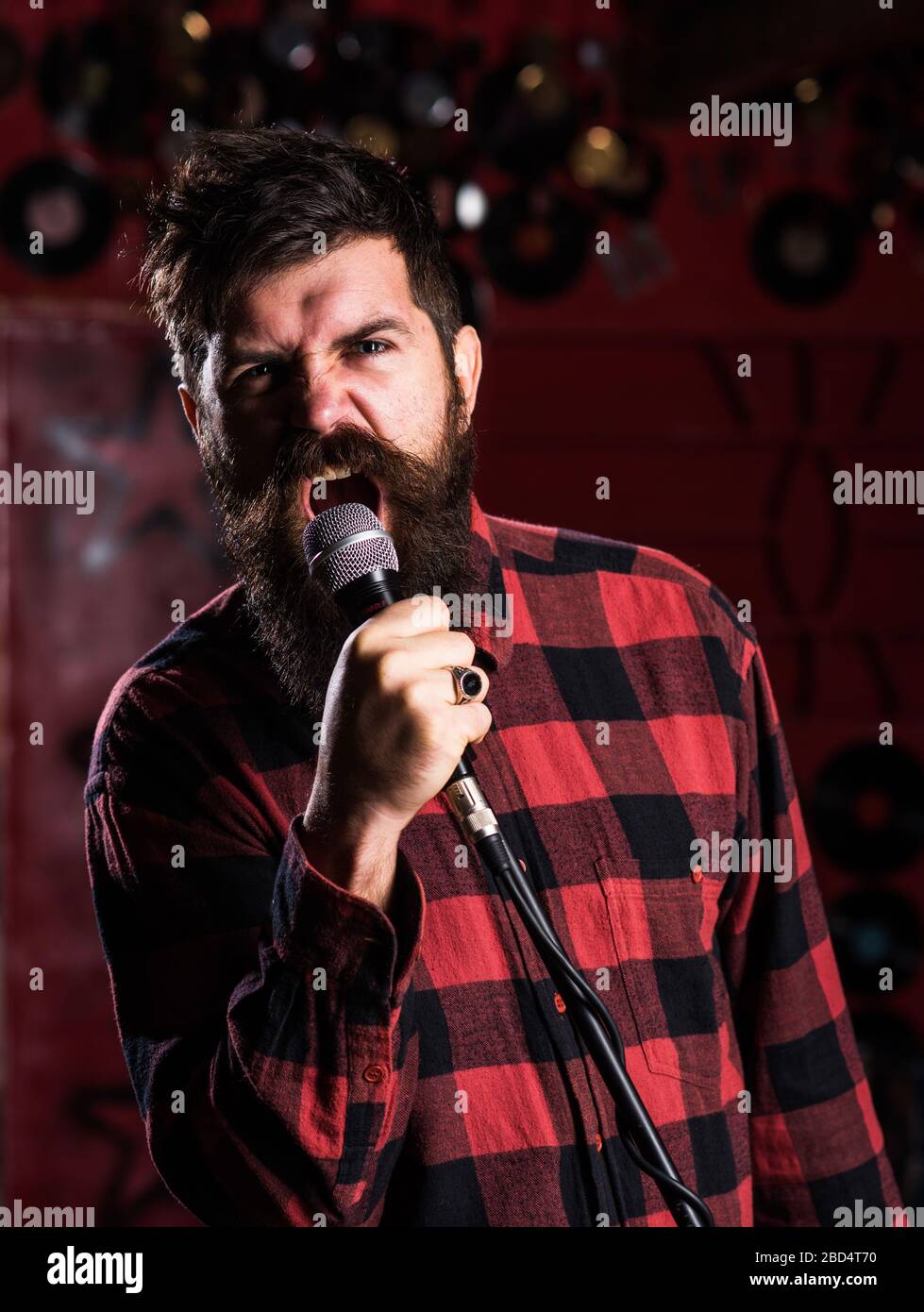 Man with enthusiastic face holds microphone, singing song, black background.  Musician with beard and mustache lighted by colorful spotlight. Singer  concept. Musician, singer singing in music hall Stock Photo - Alamy