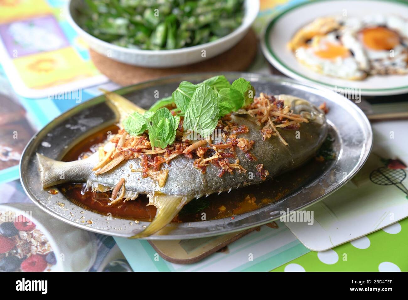 Steamed whole fish in soy sauce with ginger, garlic and mint garnish