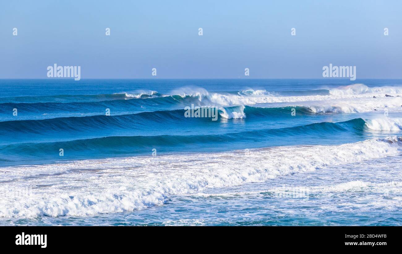 Ocean sea waves rolling towards beach crashing braking along shallow reefs andd sandbar a scenic  coastline panoramic landscape. Stock Photo
