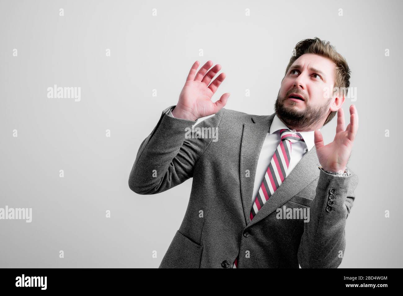 Portrait of business man wearing business clothes making scary gesture isolated on grey background with copy space advertising area Stock Photo