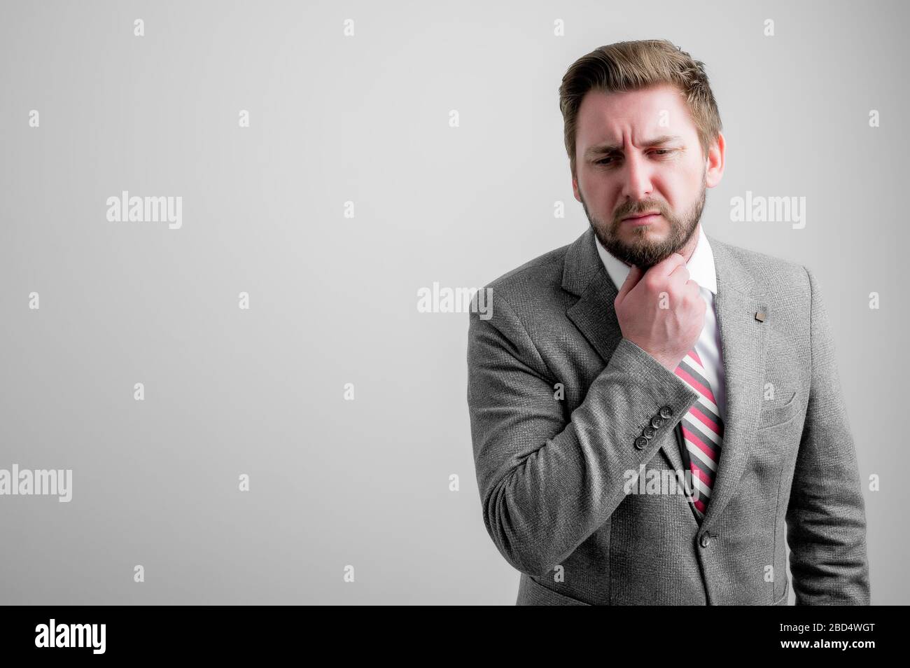 Portrait of business man wearing business clothes gesturing joint pain isolated on grey background with copy space advertising area Stock Photo