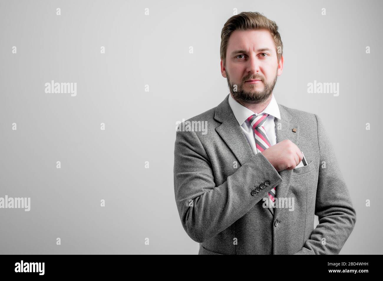 Portrait of business man wearing business clothes take out the card pocket isolated on grey background with copy space advertising area Stock Photo