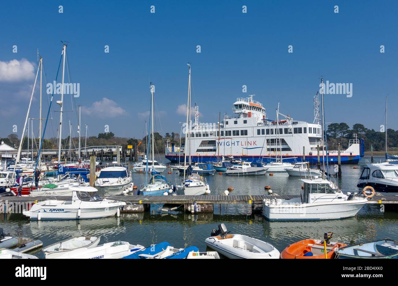 The Wightlink Ferry coming into Lymington Pier railway station and boats docked in Lymington Harbour in Hampshire, England, UK Stock Photo