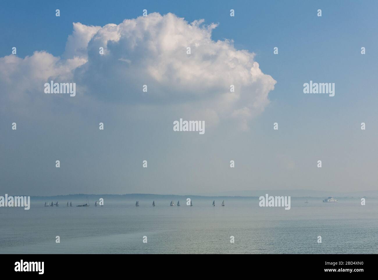 Sail boats and Isle of Wight ferry on a misty day in the Solent in