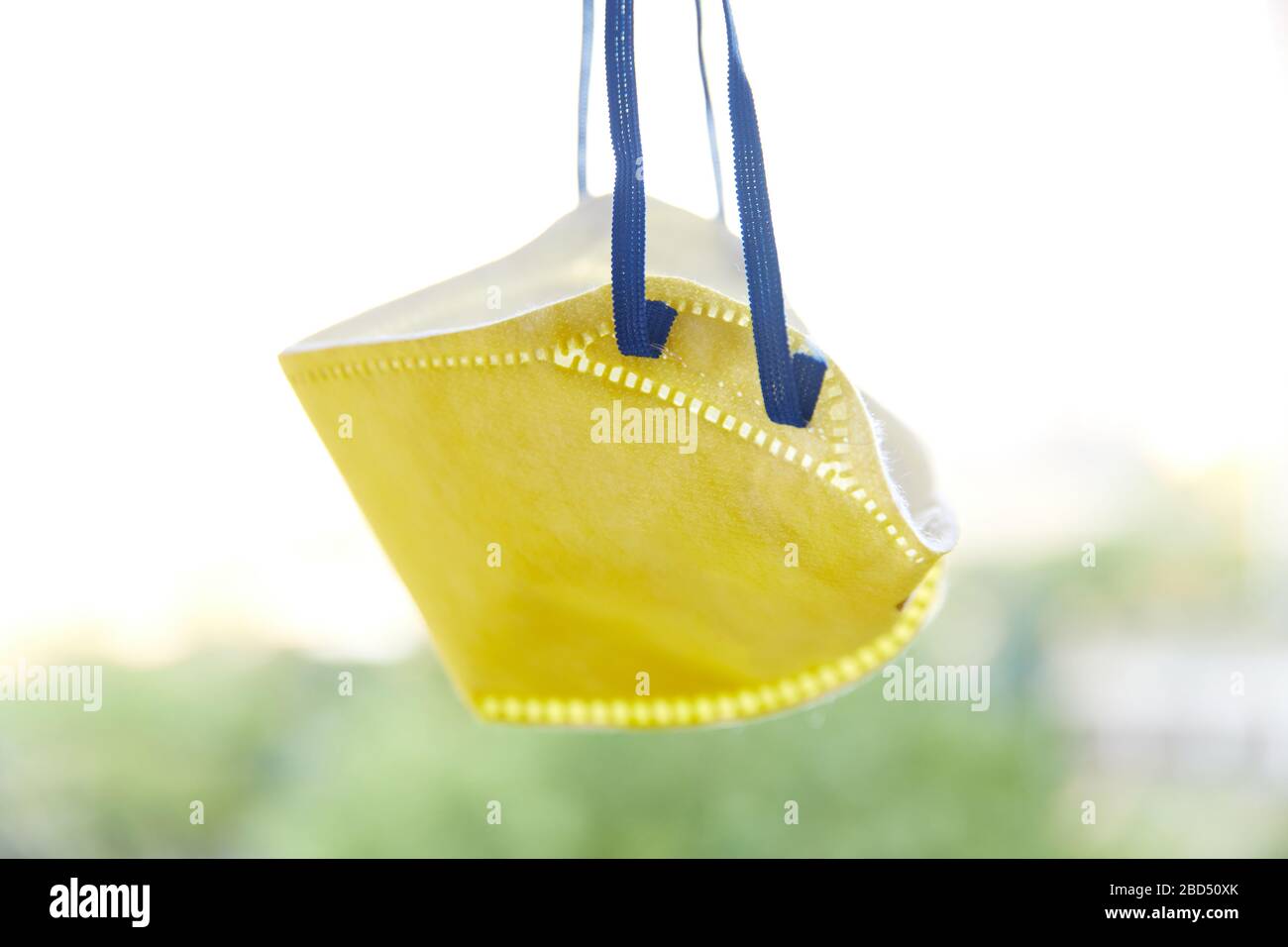 Yellow N95 Mask with blue straps hanging for prevention of aerosol