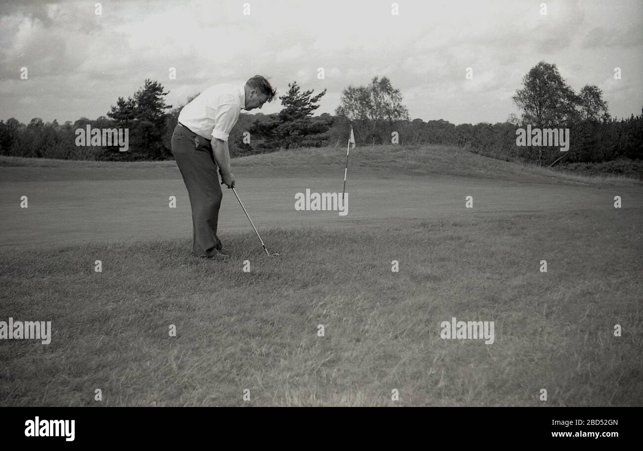 1960s, historical, Outside on an inland golf course, an adult male golfer chipping towards the flag at the edge or fringe of a putting green, England, UK. Stock Photo