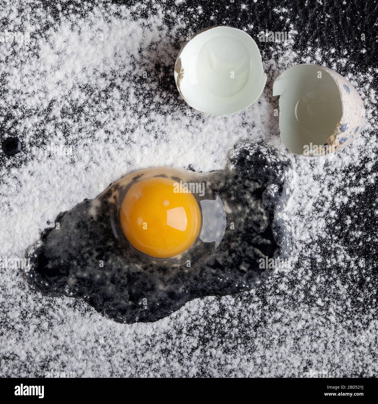 One quail egg broken into flour on black background Stock Photo