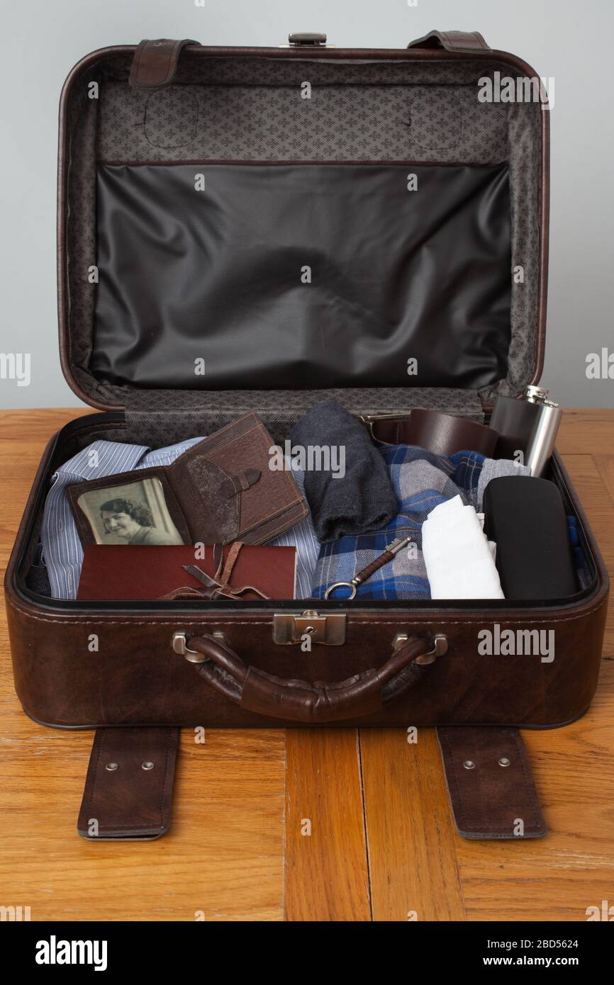 An old brown leather suitcase open showing old items and retro items including an old wallet and key Stock Photo