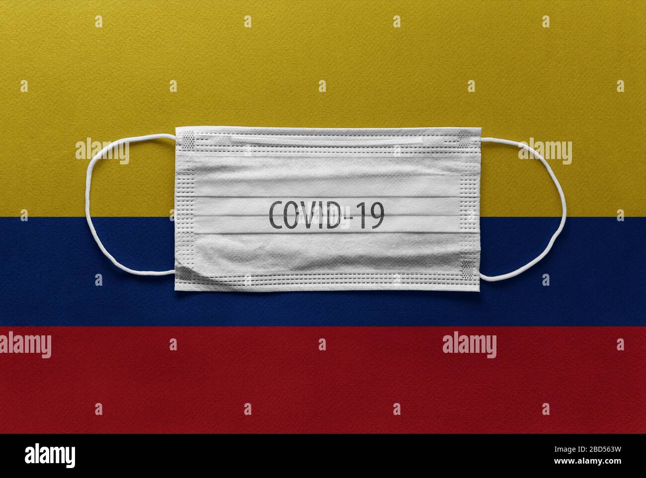 An individual face medical surgical mask on Colombia National Flag Background. Health mask. Protection against COVID-19 virus, influenza, SARS. Save C Stock Photo