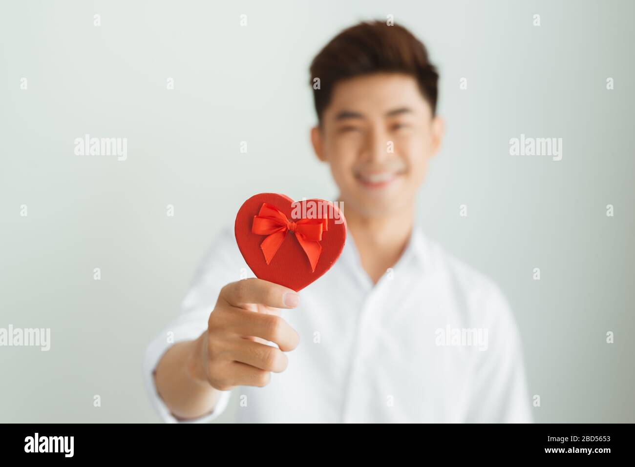 Handsome young man holding red heart box on white background Stock ...