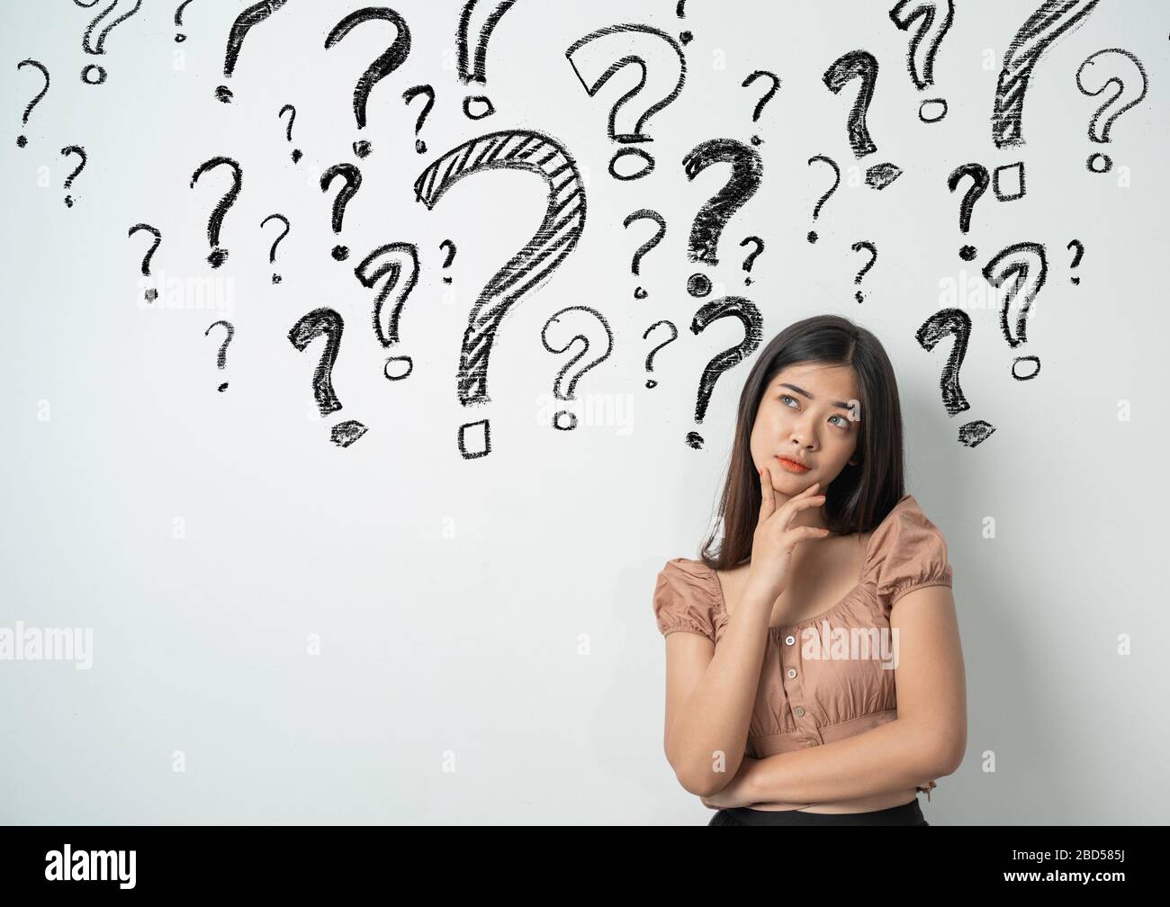 young woman with question mark on a gray background Stock Photo - Alamy