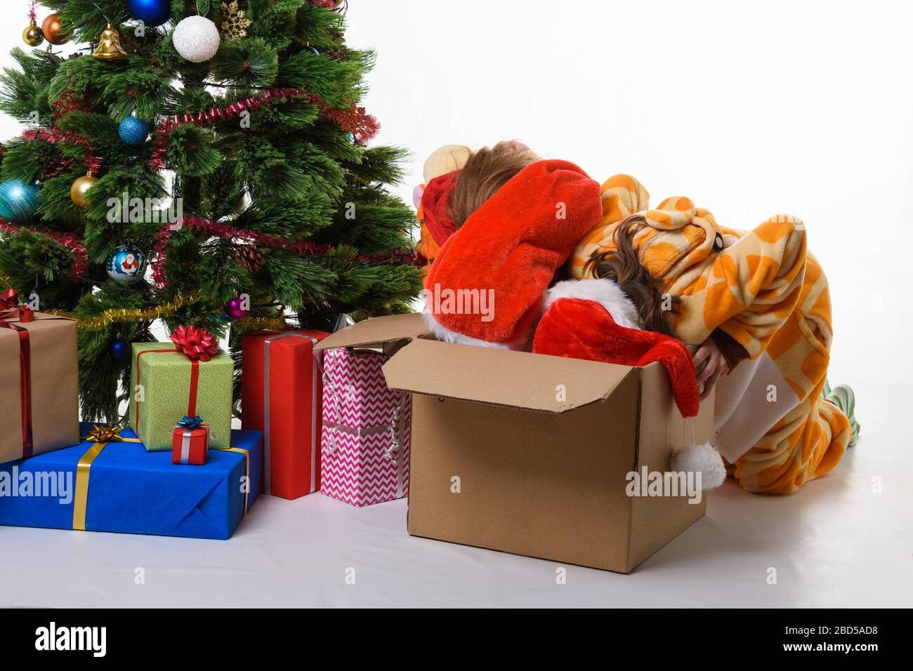Two girls crawled headlong into a box with New Year's toys Stock Photo